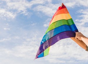 homem-com-bandeira-grande-em-lgbt-cores-e-ceu-azul_23-2148120273.jpg