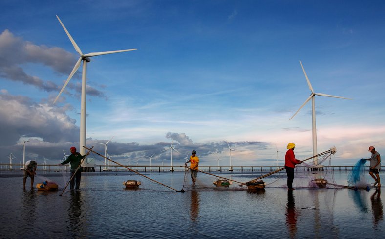 Fishermen work near renewable energy wind turbines